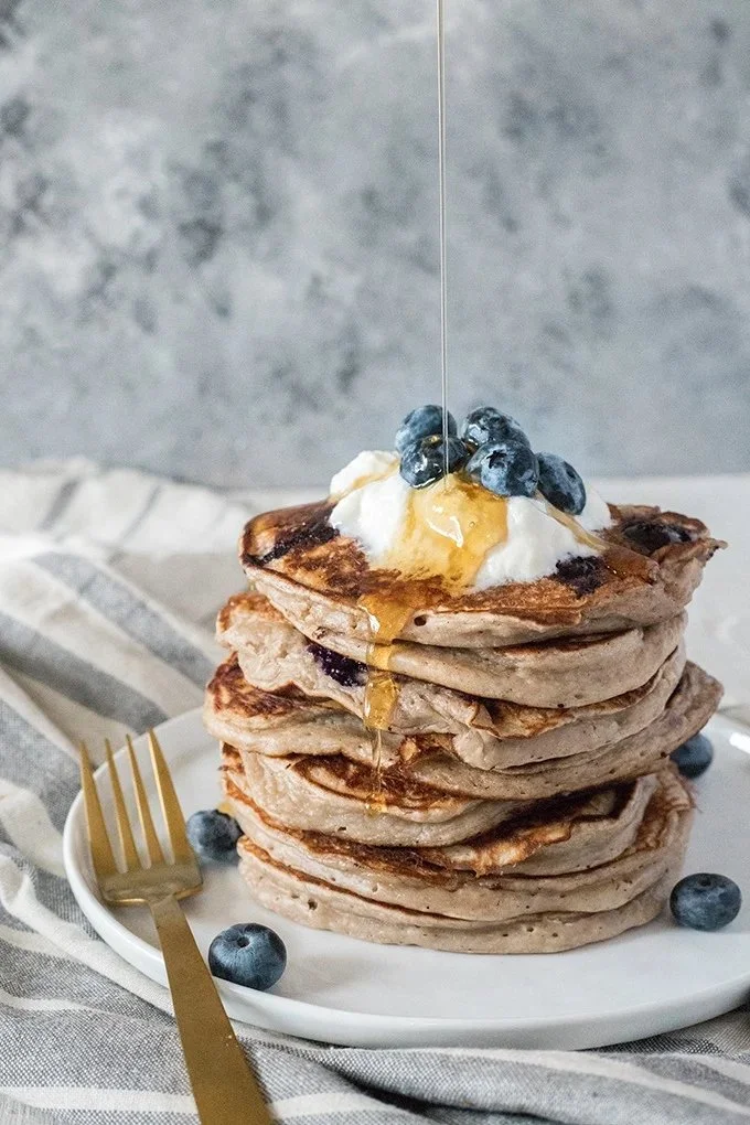 Delicious blueberry kefir pancakes stacked on a plate with syrup