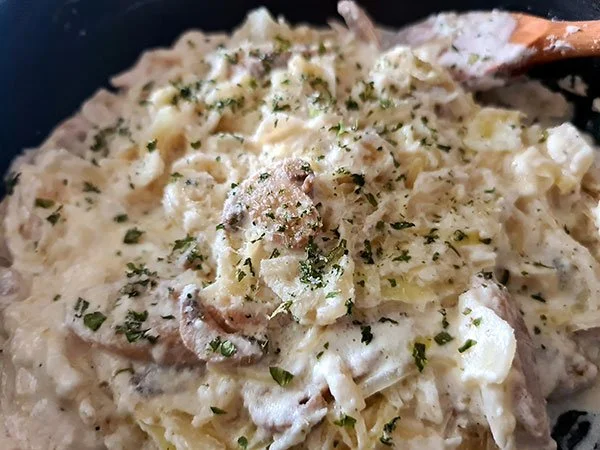 A bowl of creamy Cabbage Alfredo topped with parsley and grated cheese.