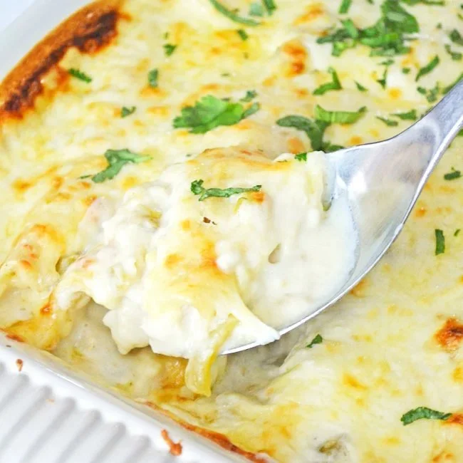Creamy chicken green chile enchiladas topped with cheese and cilantro