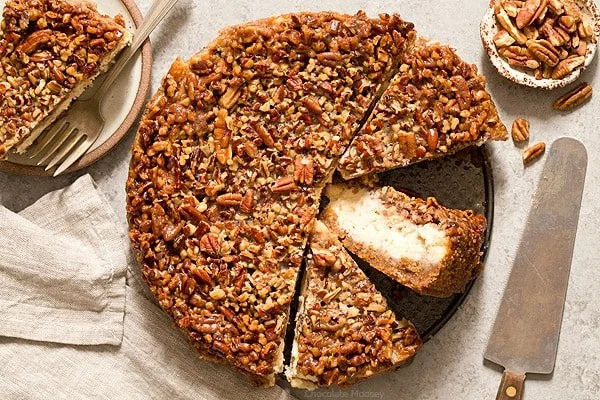 Slice of creamy pecan cheesecake pie with a garnish of pecans on top
