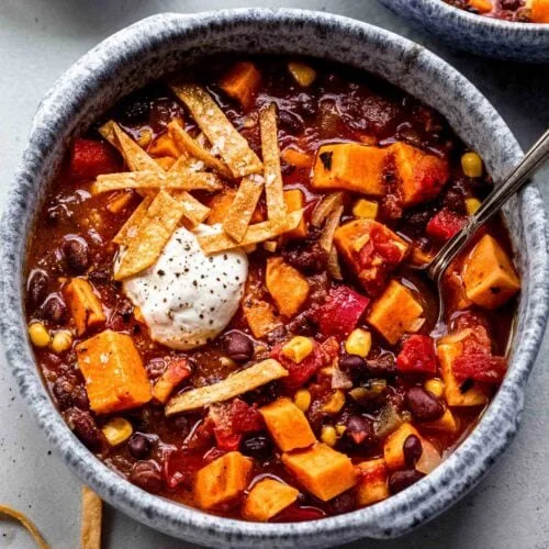 Bowl of creamy Sweet Potato Black Bean Chili topped with fresh herbs