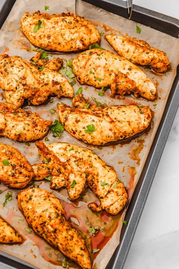 Oven baked chicken tenders without breading on a plate, garnished and ready to serve