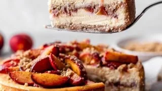Slice of Peach Cobbler Cheesecake Fusion topped with fresh peaches and whipped cream